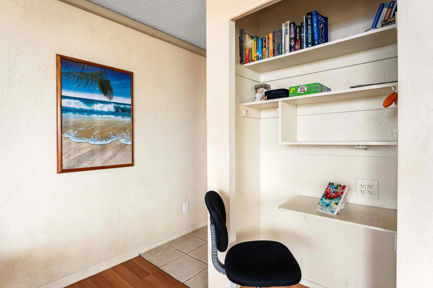 Un pequeño rincón de estudio con escritorio integrado, estantes y una silla.