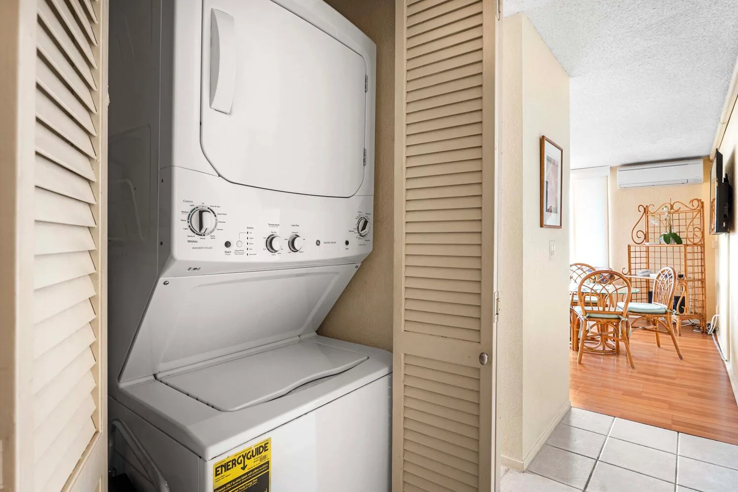 Zona de lavandería con lavadora y secadora apiladas junto a un comedor.