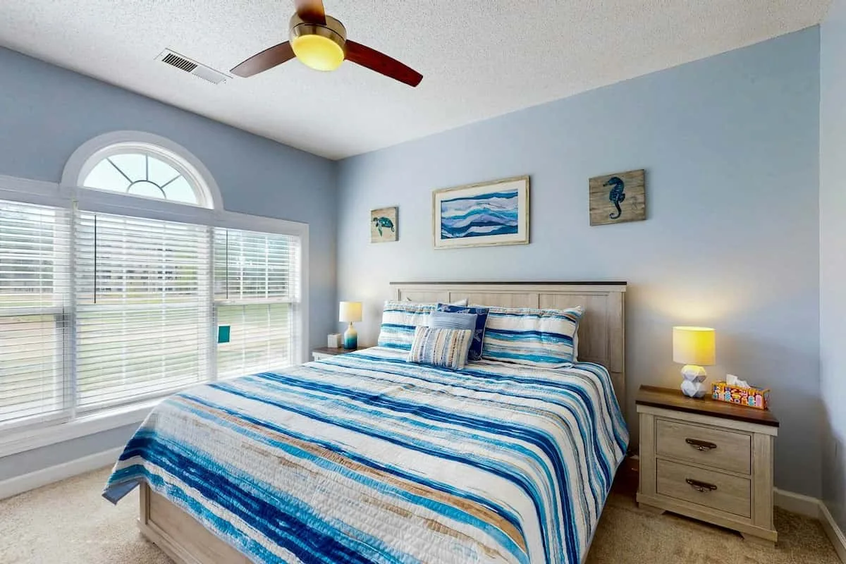 Un dormitorio con una cama vestida con ropa de cama a rayas azules y blancas.