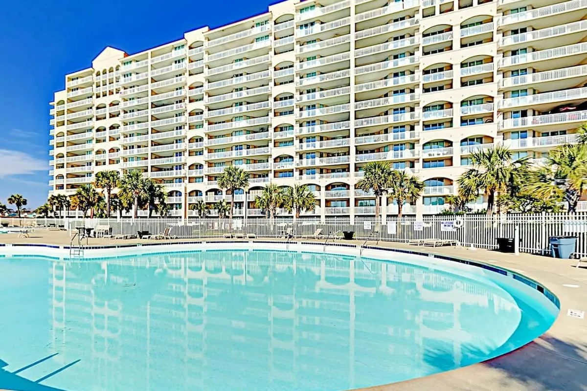 Un gran edificio se alza detrás de una piscina curva.