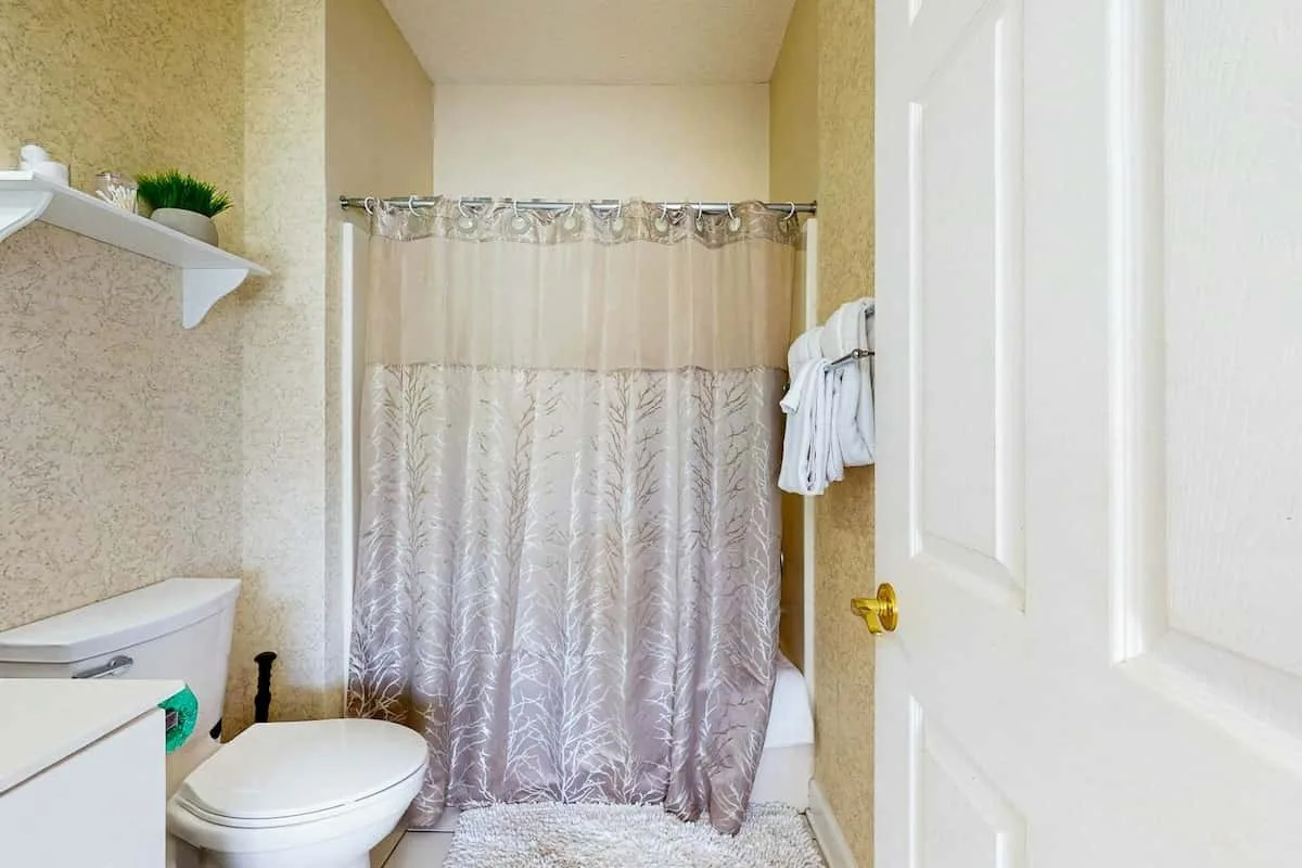Un baño con una ducha con cortina y un inodoro.