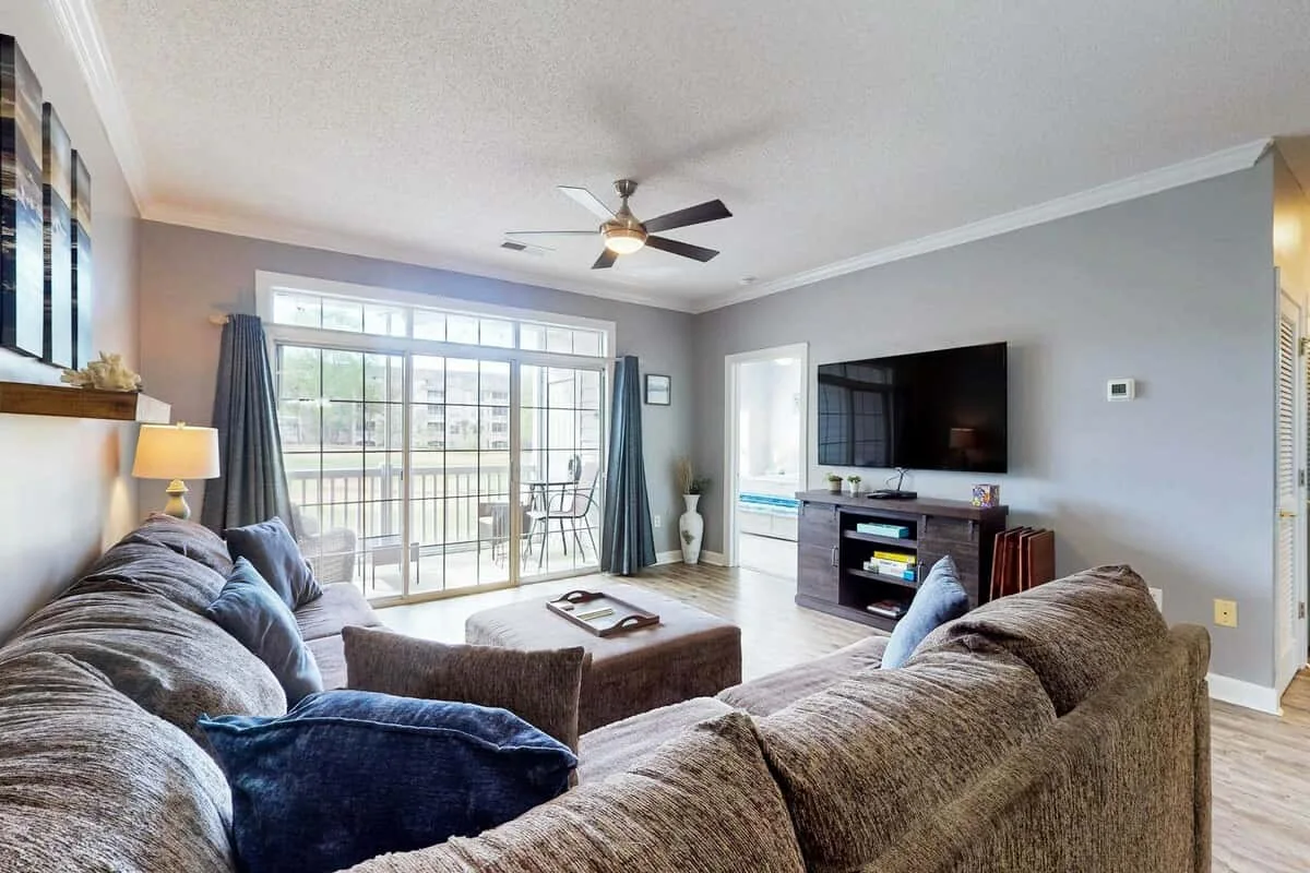 Living room with seating, a television, and large glass doors.