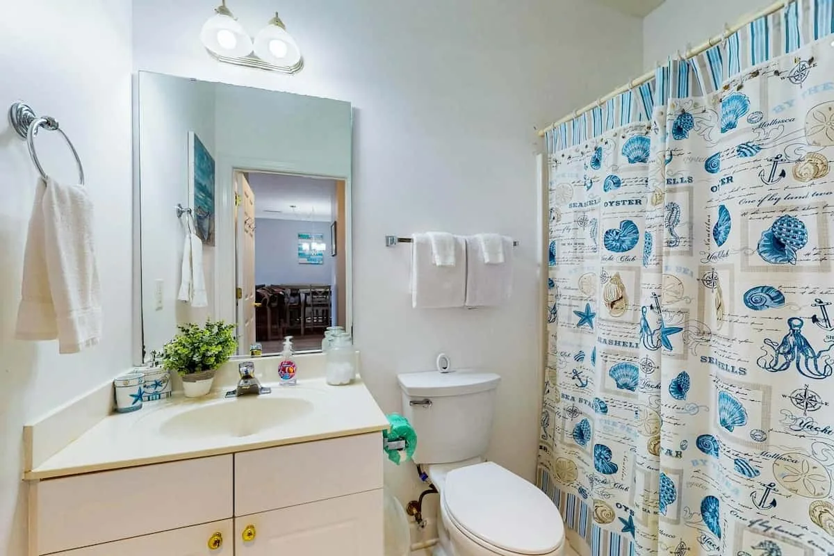Un baño con lavabo, inodoro y cortina de ducha estampada.