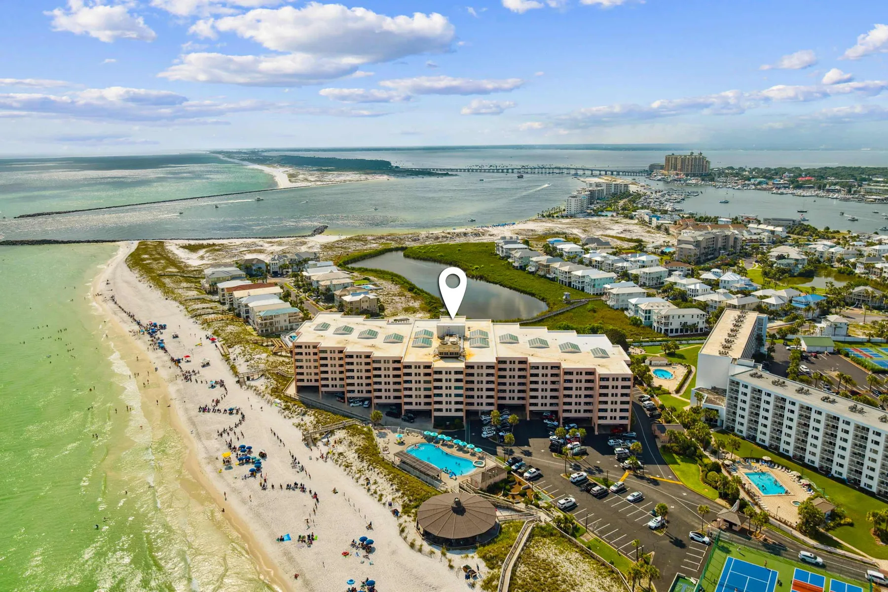 Vista aérea de edificios frente a la playa, costa arenosa y agua turquesa.