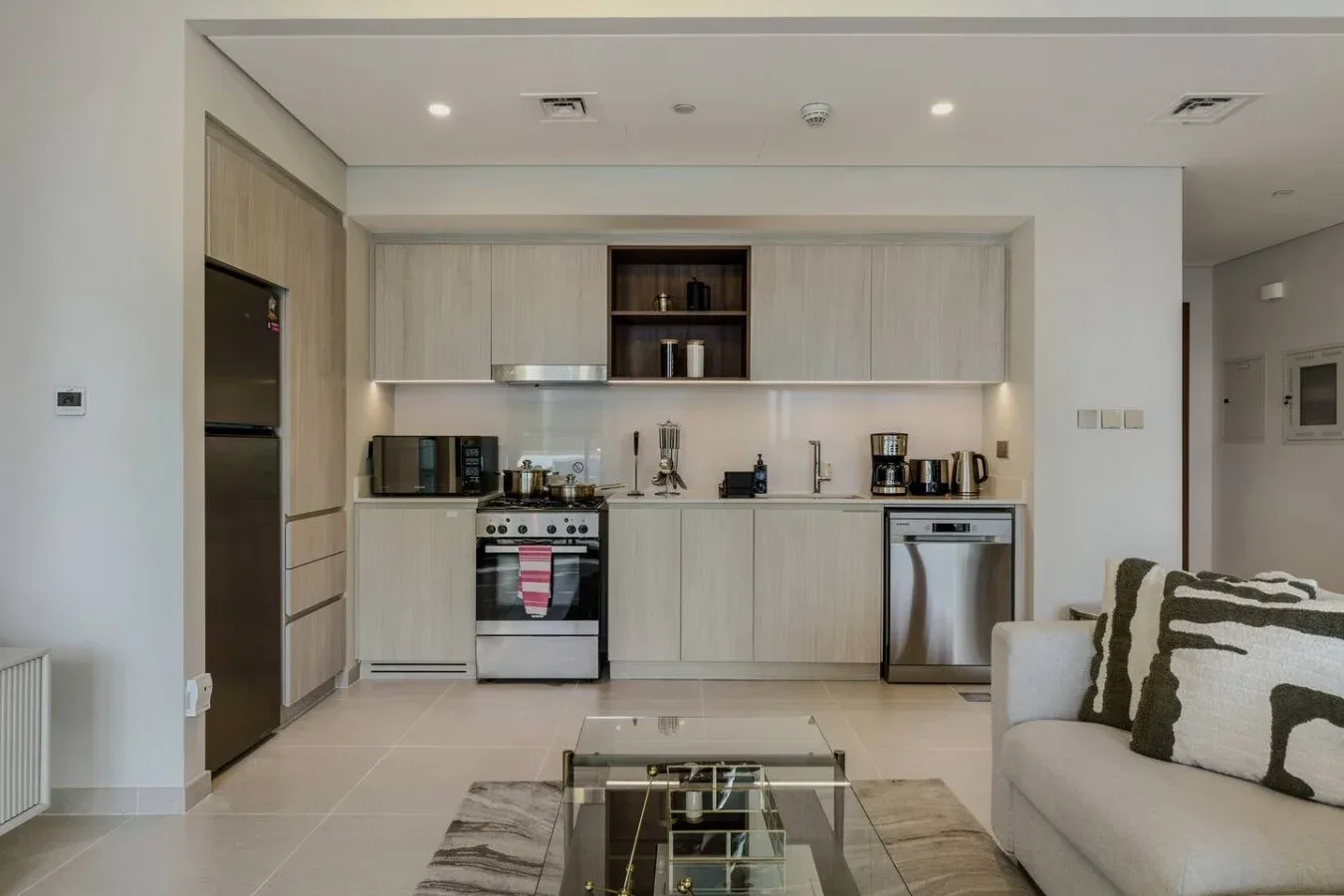 Una cocina moderna con gabinetes claros y una sala de estar en primer plano.