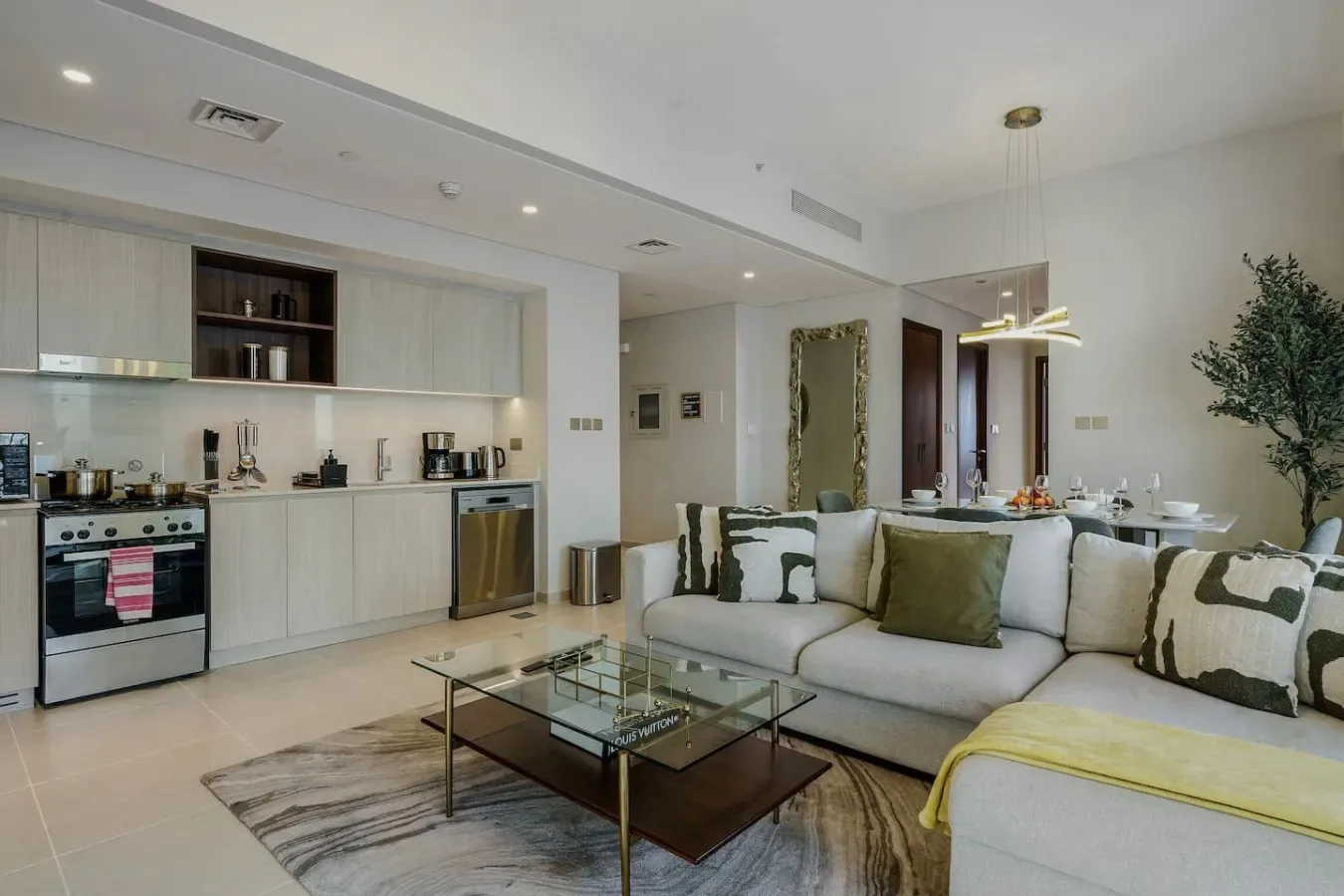 Una cocina abierta al salón, con un sofá claro y una mesa de centro de cristal.