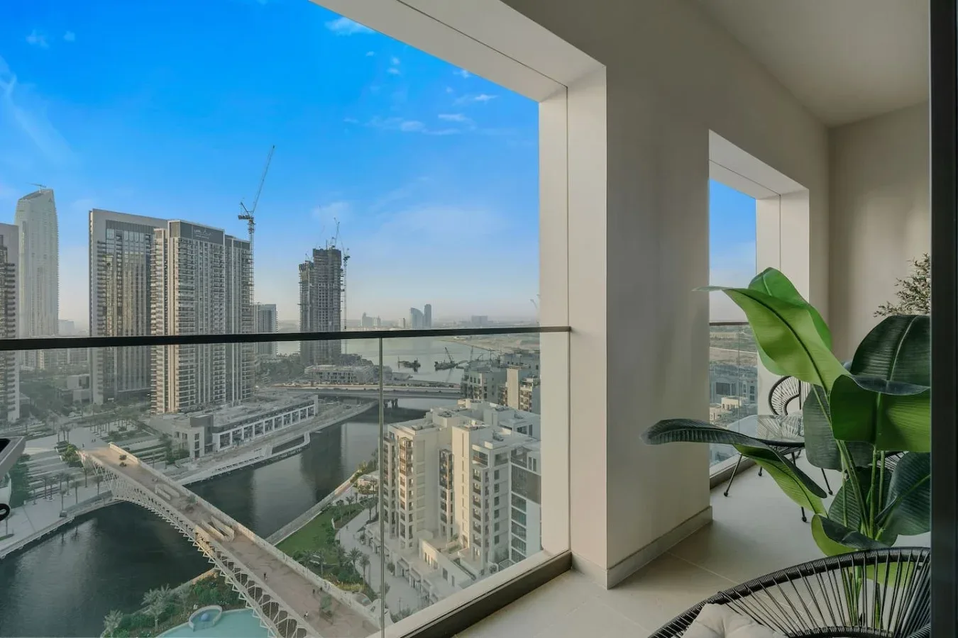 Un interior luminoso se abre a una vista de la ciudad, con plantas junto a las ventanas.