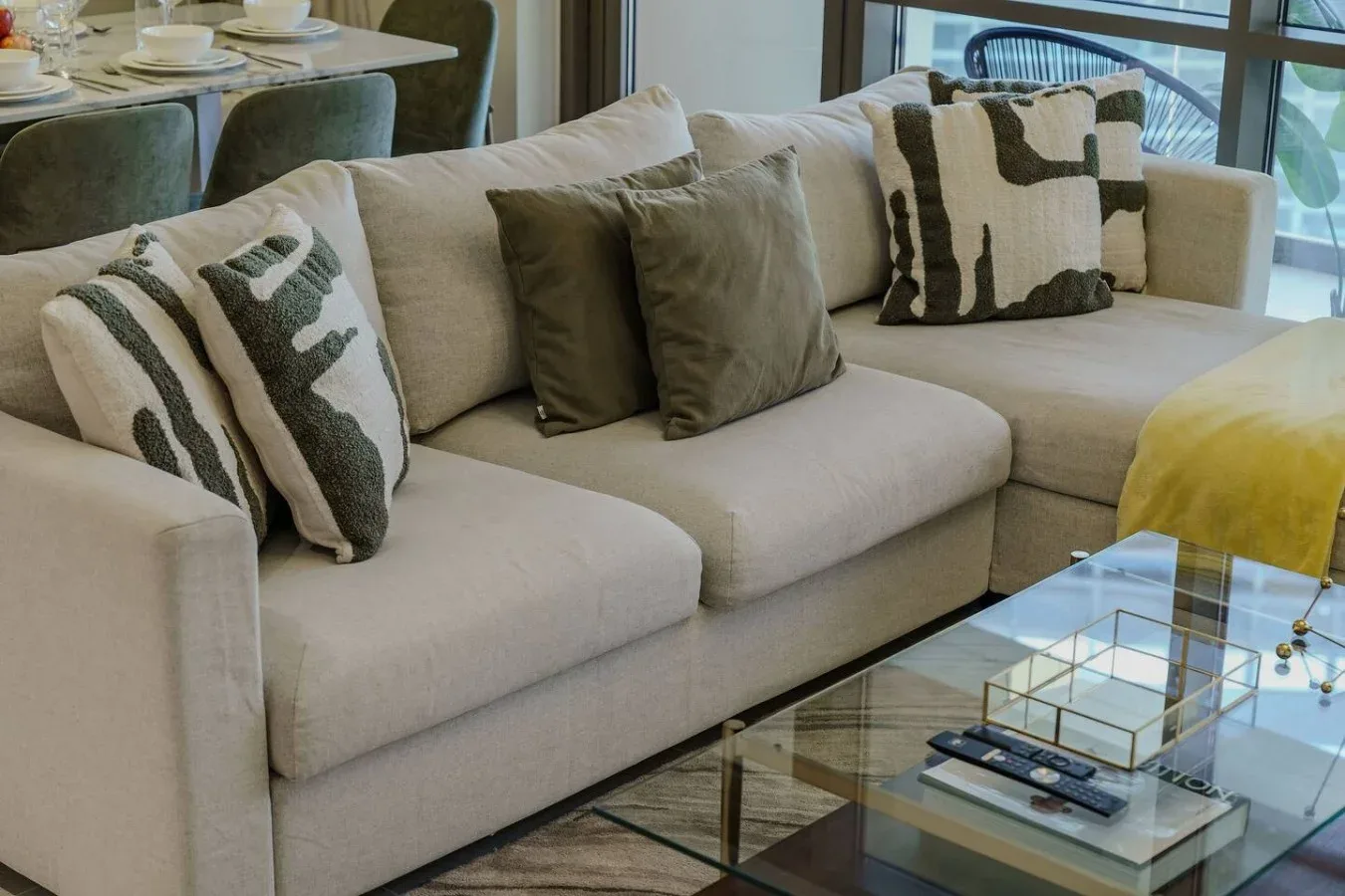 Una sala de estar con un sofá seccional beige y cojines estampados.