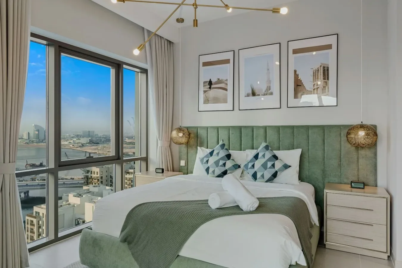 Un dormitorio con una cama, un cabecero verde y grandes ventanas con vistas a la ciudad.