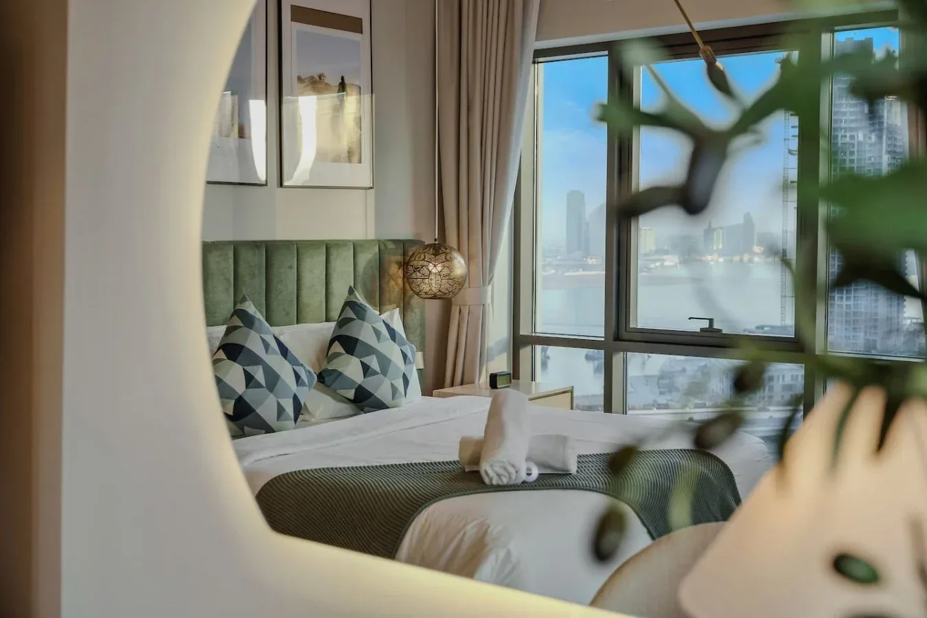 Un dormitorio con una cama bien arreglada junto a grandes ventanas con vistas al agua.