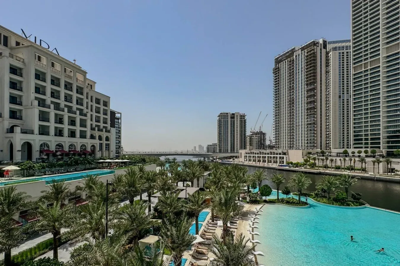 Una piscina al aire libre está rodeada de jardines y edificios altos de apartamentos.