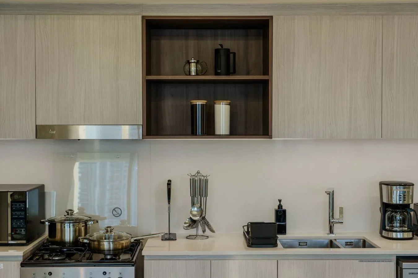 Una cocina moderna con gabinetes claros, una placa de cocción y un fregadero.