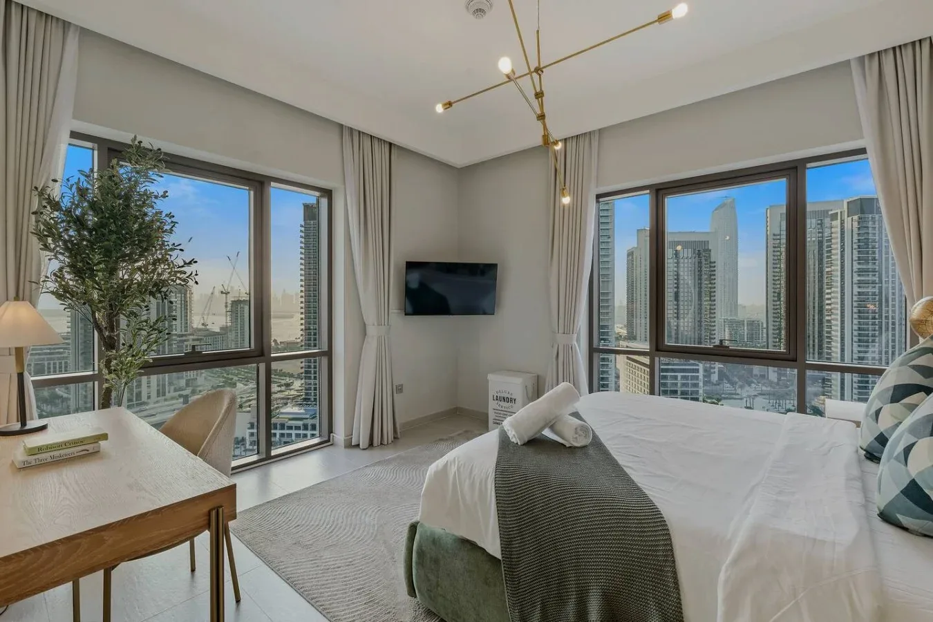 Un dormitorio luminoso con una cama grande, ventanales y vistas a la ciudad.