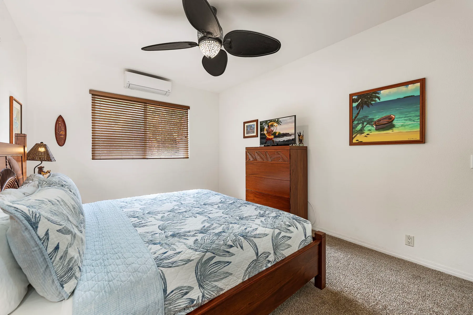 A bedroom with a bed, a wooden dresser, and a ceiling fan.