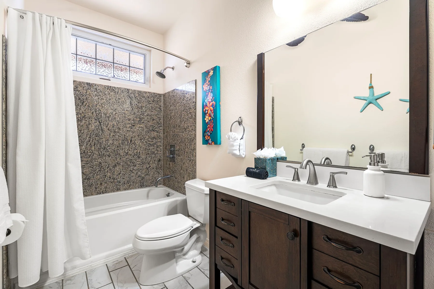 A bathroom with a bathtub, toilet, and double vanity.