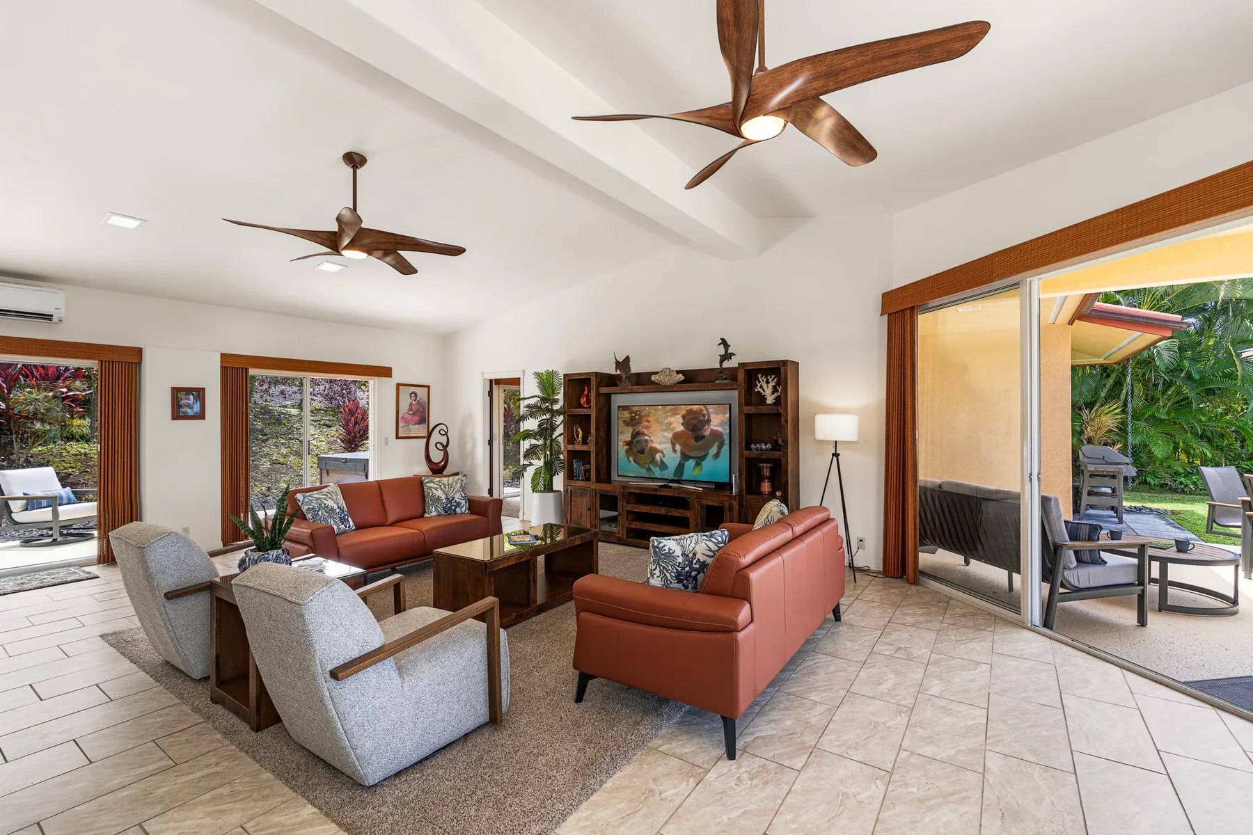 A bright living room with seating, a television, and sliding doors opening onto a patio.