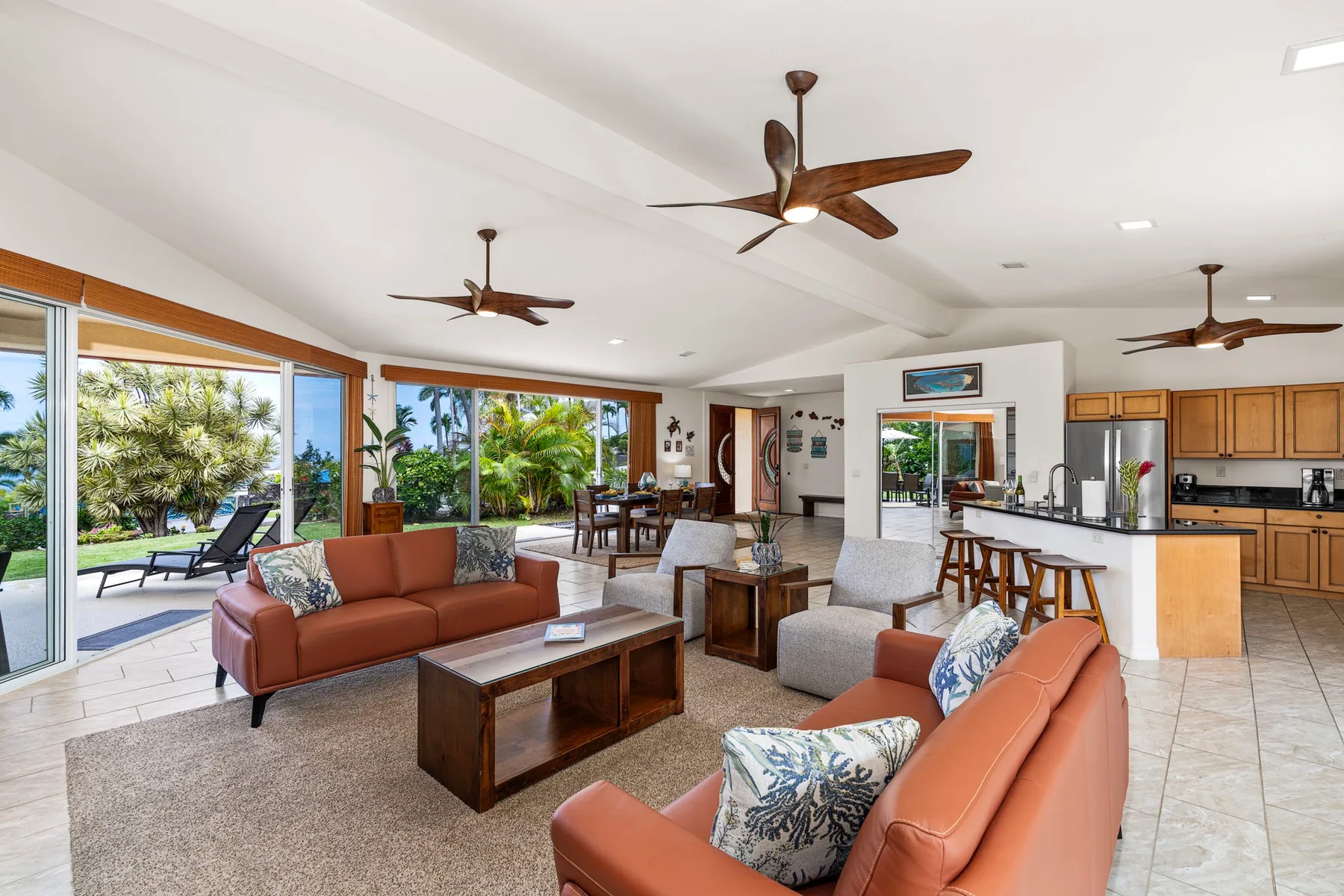 An open living and dining area with seating beside large windows overlooking greenery.