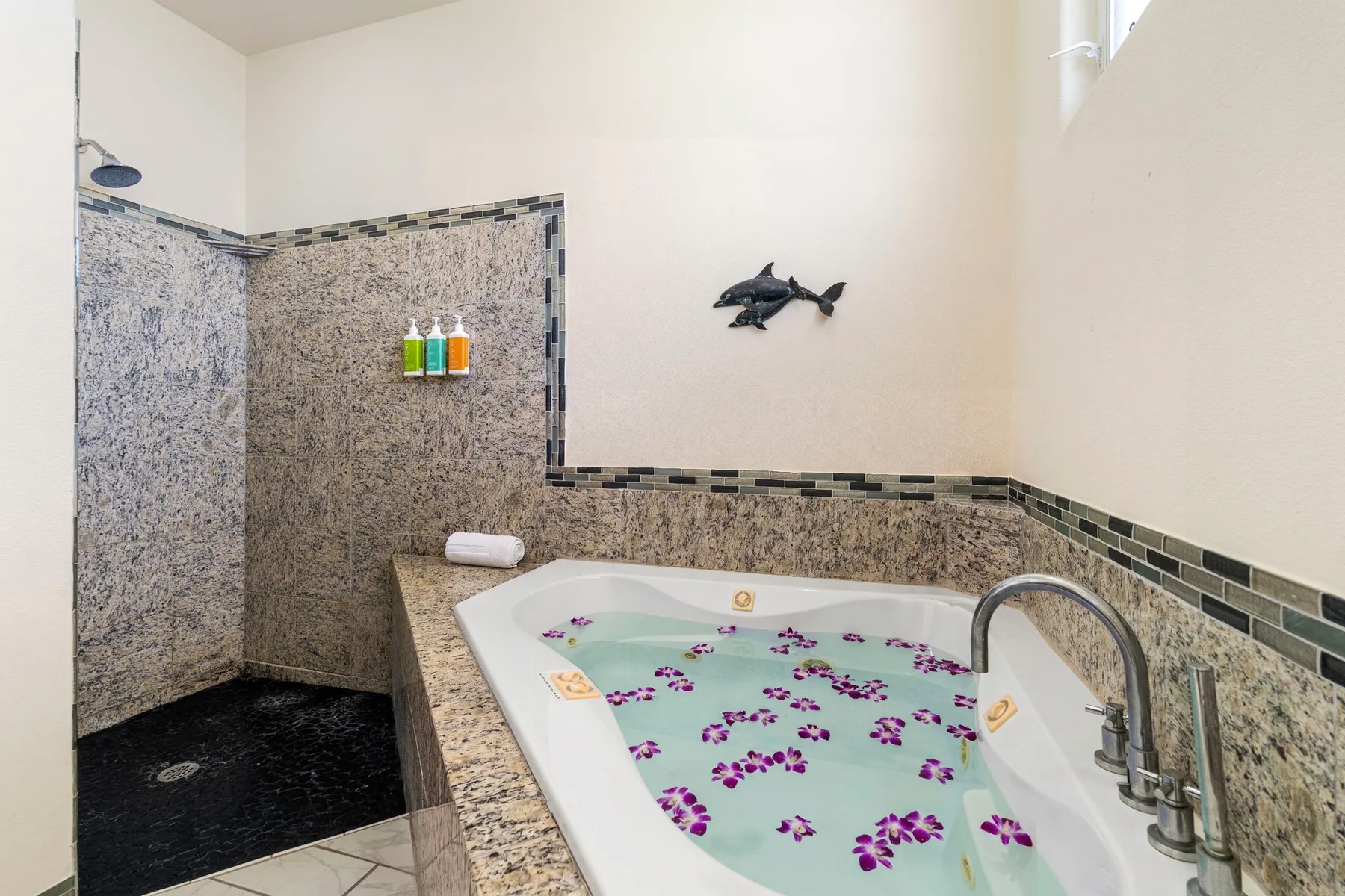 A bathroom with a built-in bathtub filled with water and floating flowers.