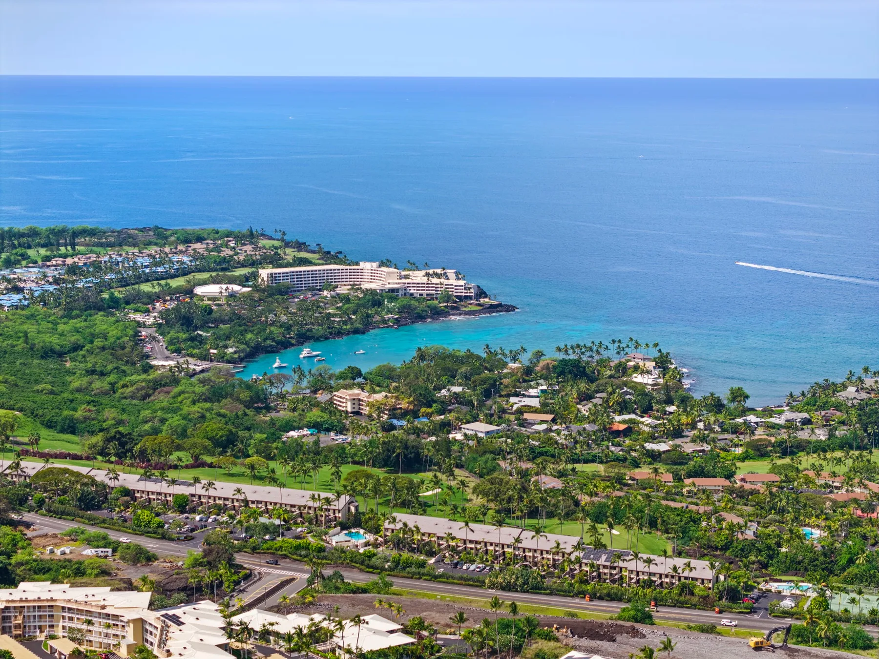 Aerial view of a tropical coastline with green vegetation and blue ocean.
