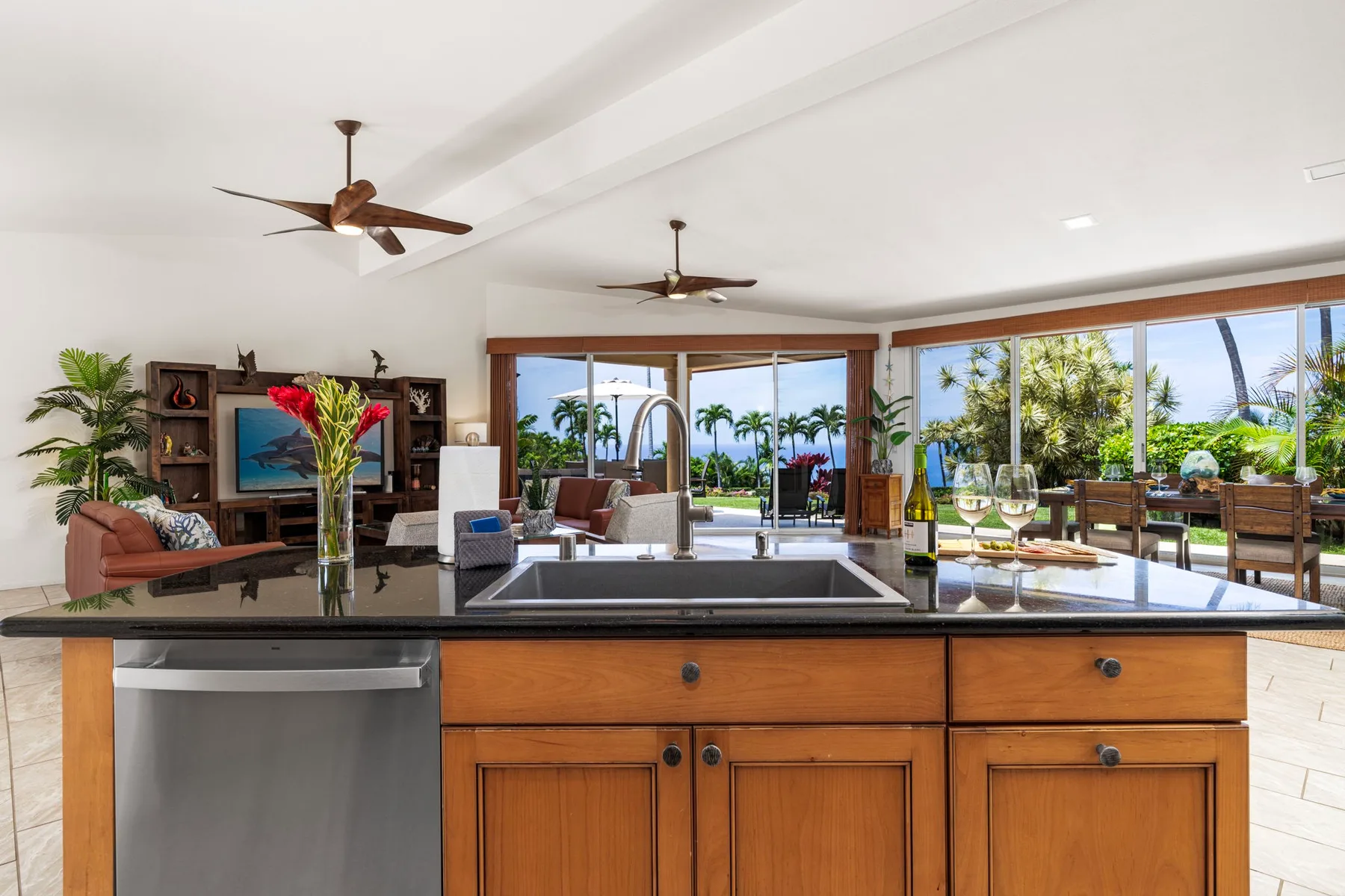 An open-plan kitchen and living area with large windows overlooking palm trees.