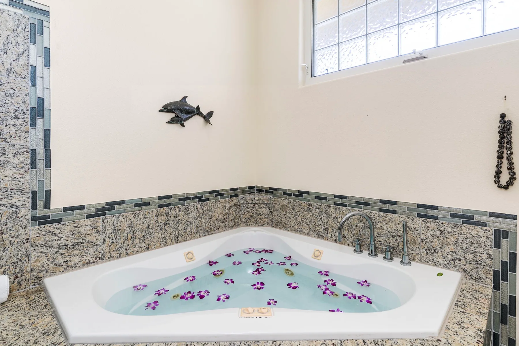 A bathroom with a corner whirlpool tub filled with water and flower petals.