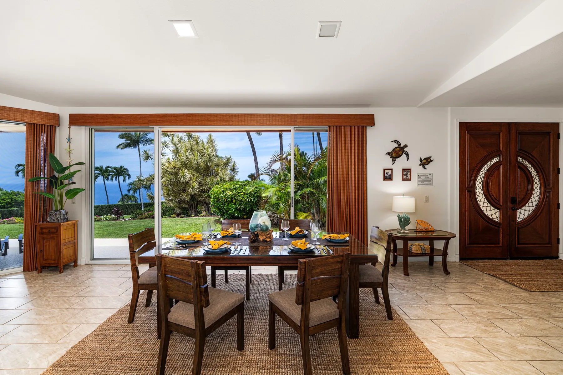 A dining area with a wooden table and chairs facing sliding glass doors to a garden.