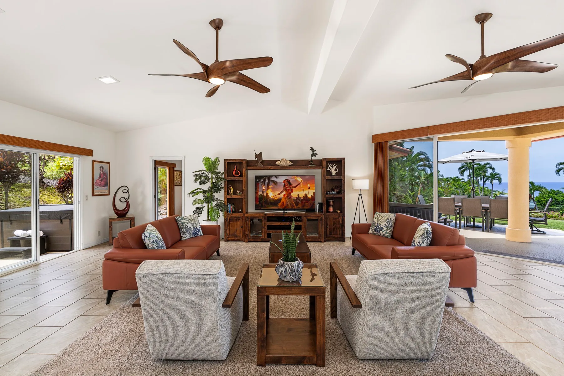 A bright living room with seating arranged around a wooden coffee table and television.