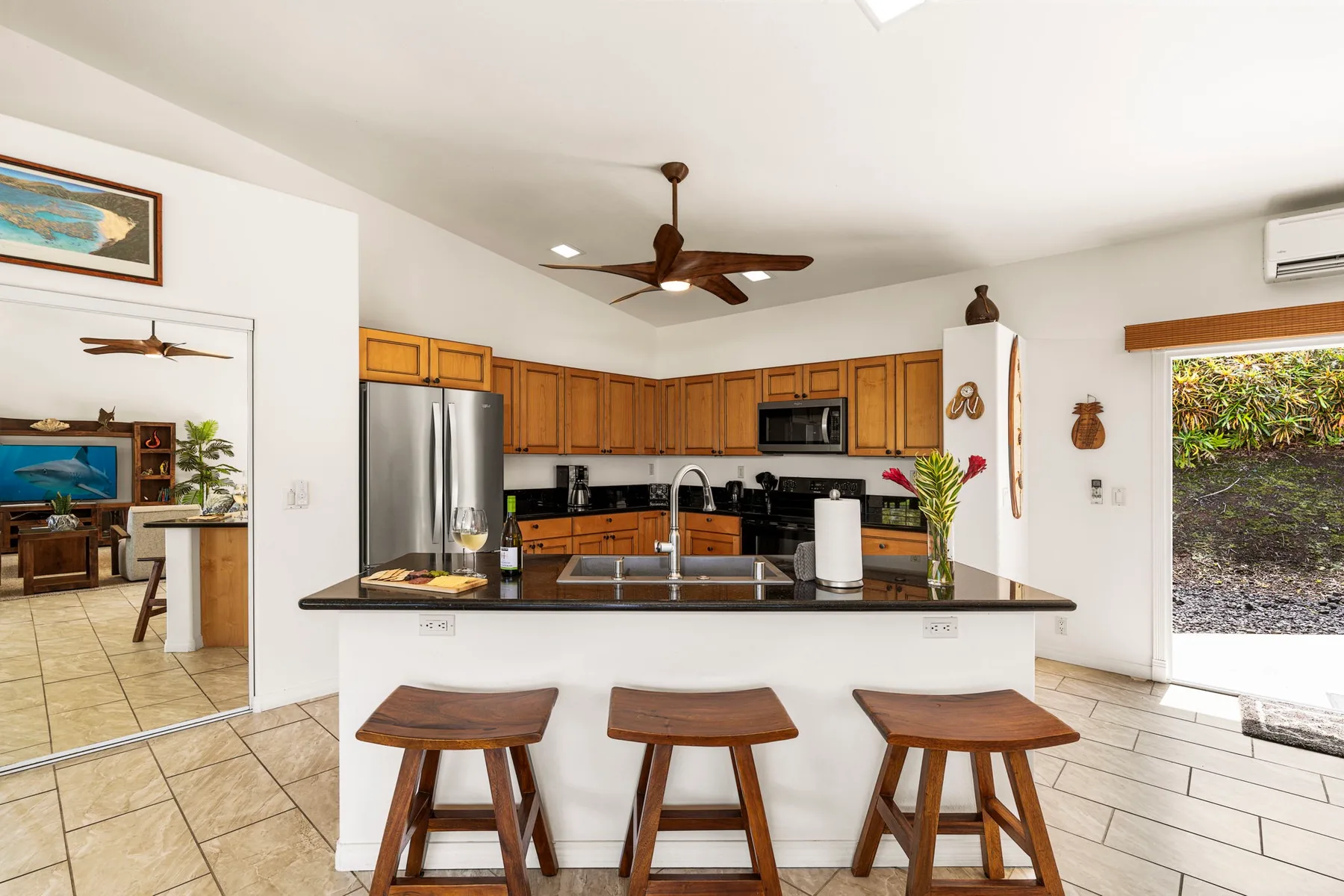 An open kitchen with a counter, wooden cabinets, and three stools.