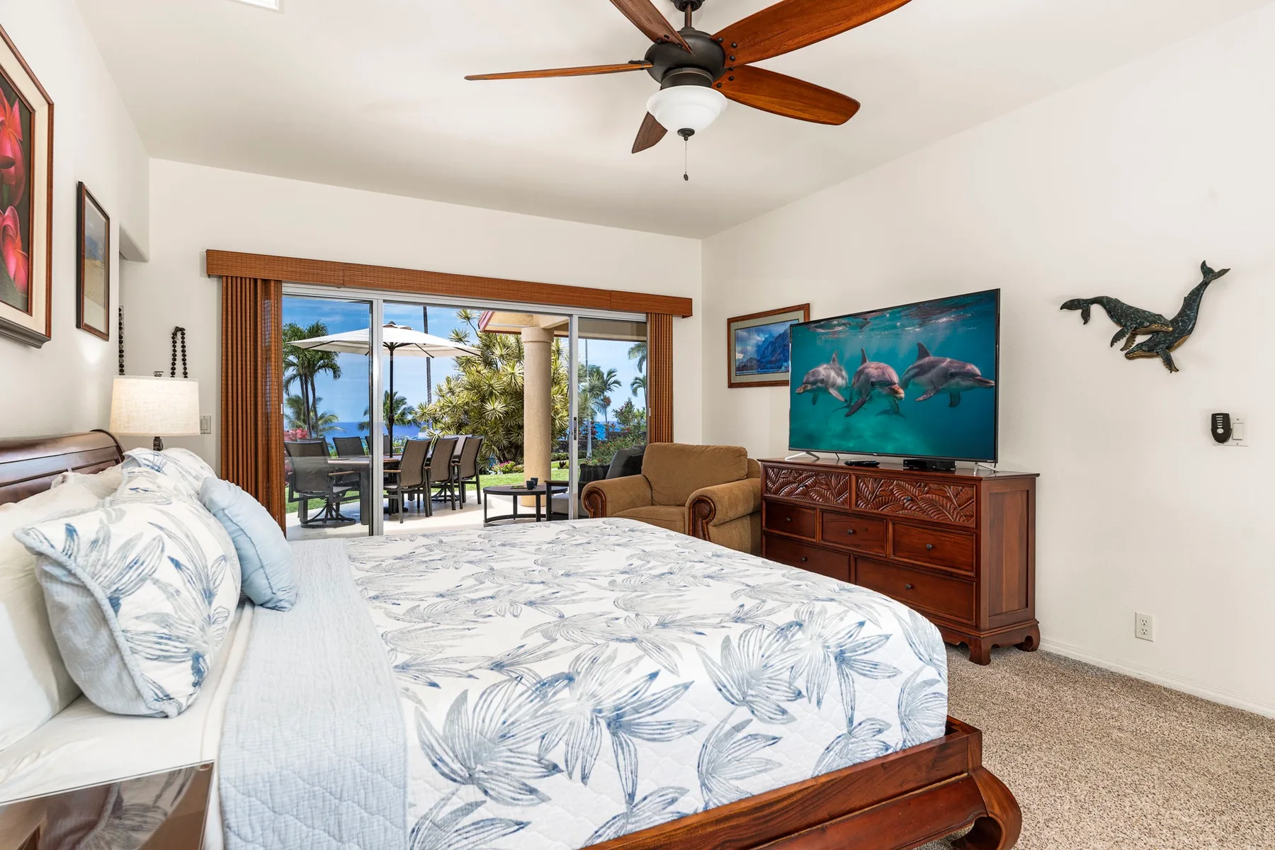 A bedroom with a bed, television, and sliding glass doors opening onto a patio.