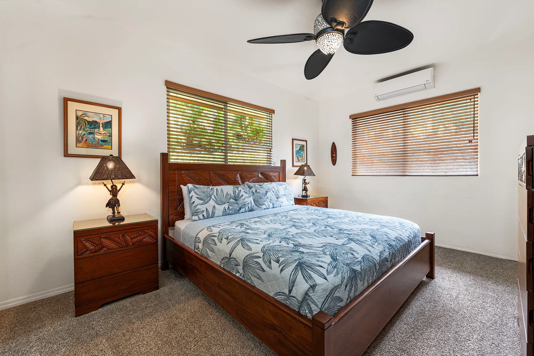 Bedroom with a wooden bed, patterned bedding, and windows with blinds.