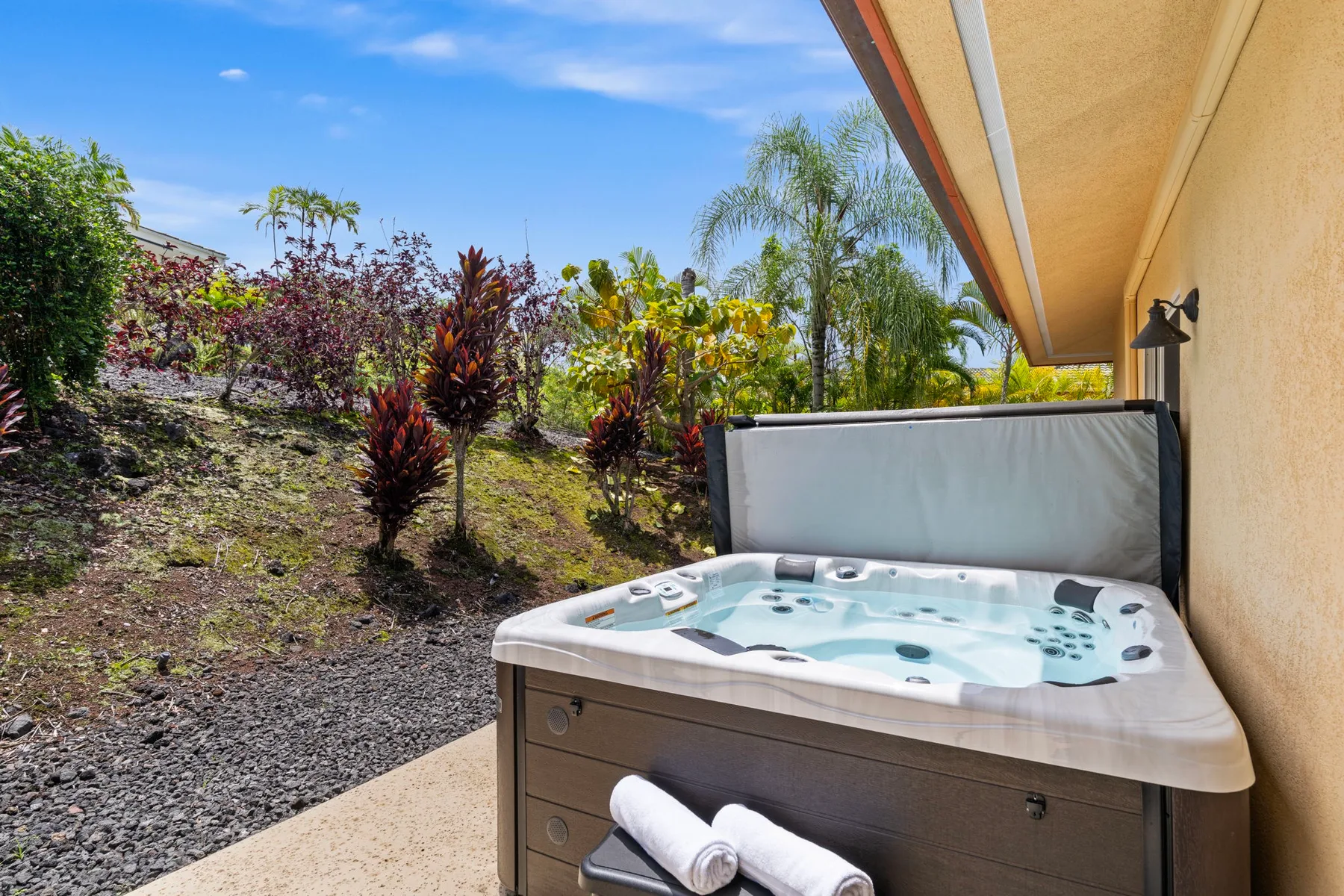 Outdoor hot tub beside a landscaped garden and the building wall.