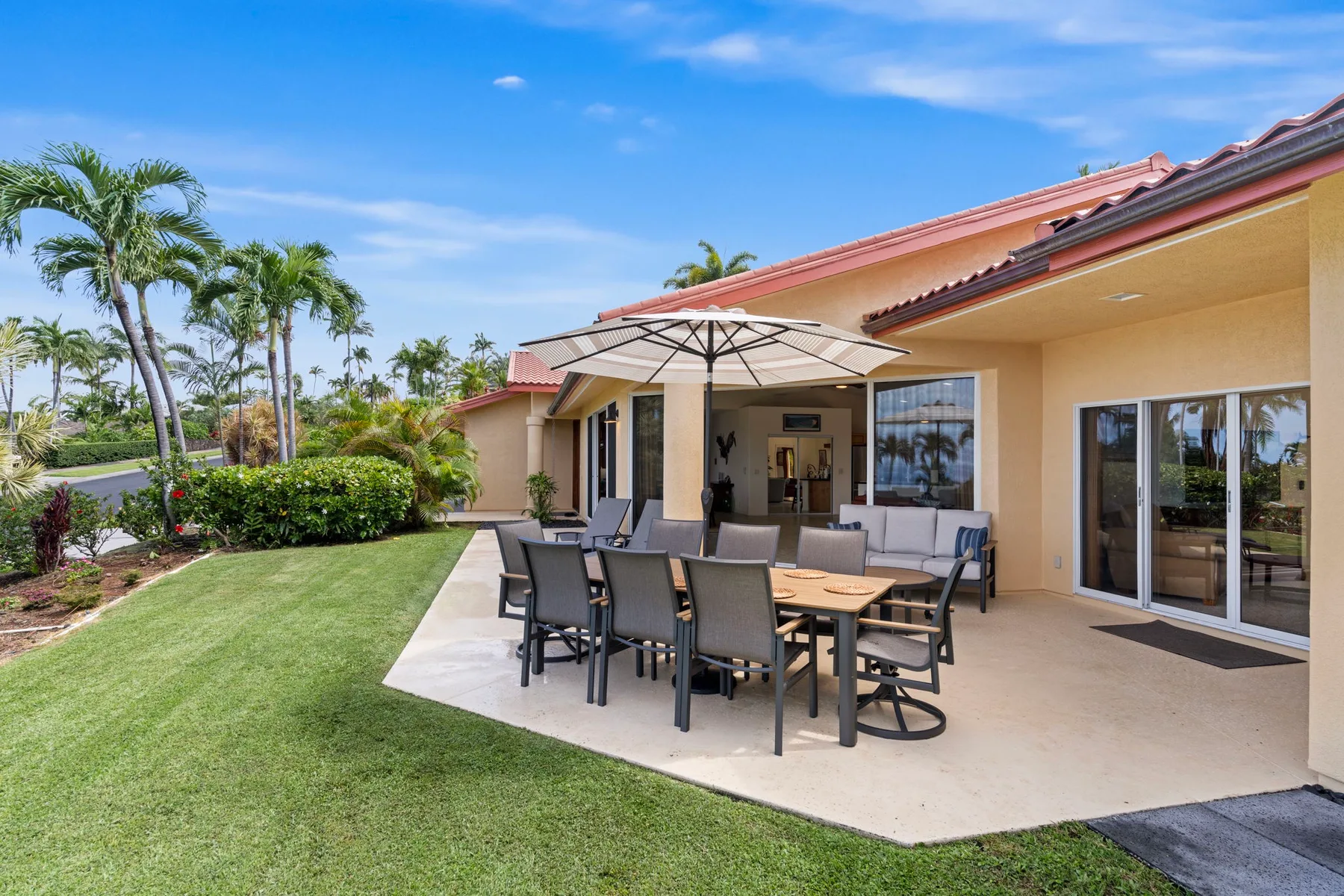 Outdoor dining area with a table and seating beneath a large umbrella.
