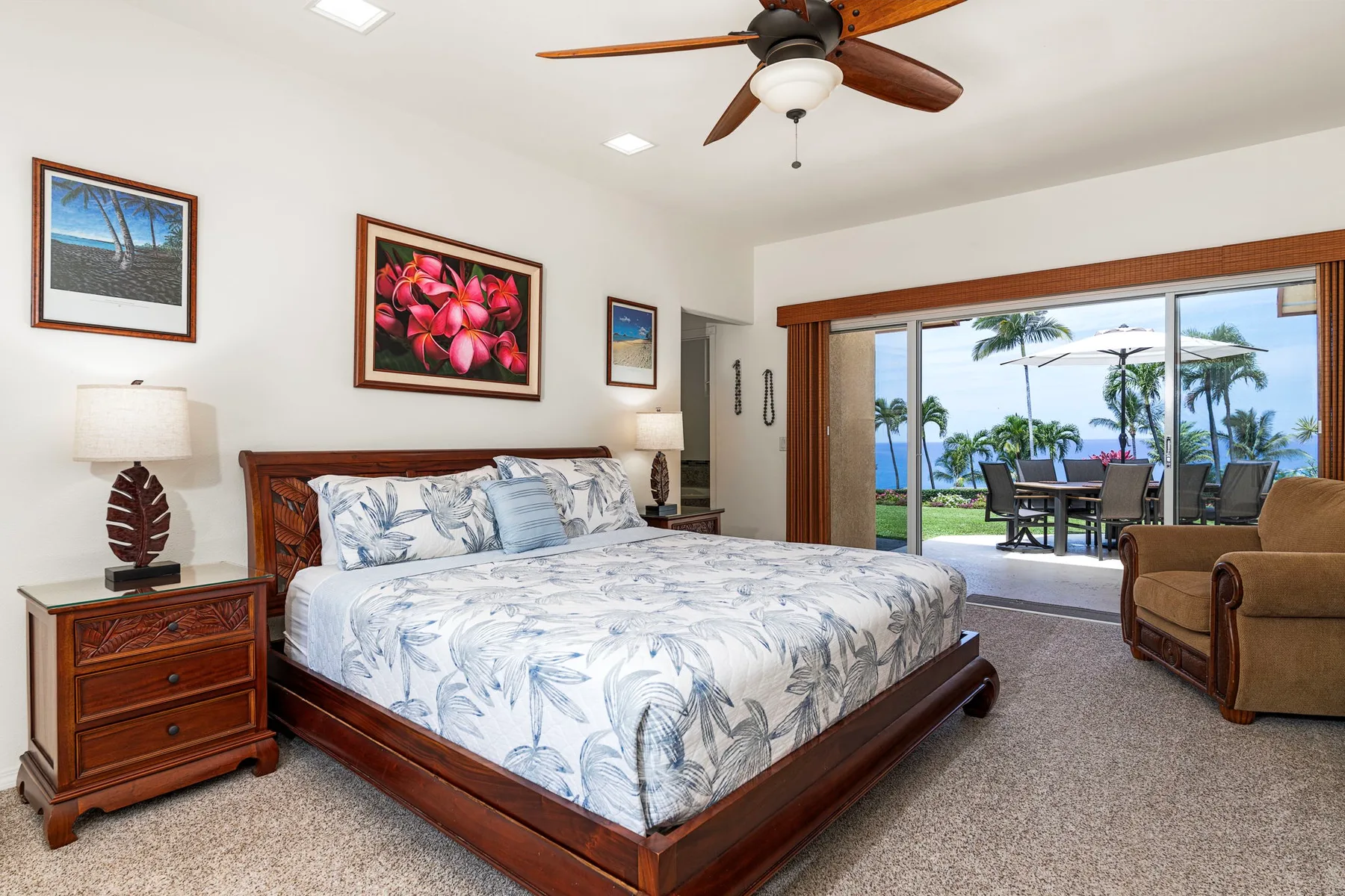 A bedroom with a large bed and sliding glass doors opening onto a patio.
