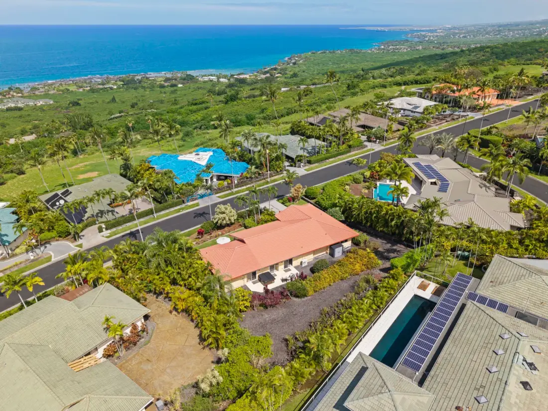 Aerial view of homes and landscaped grounds along a coastal shoreline.