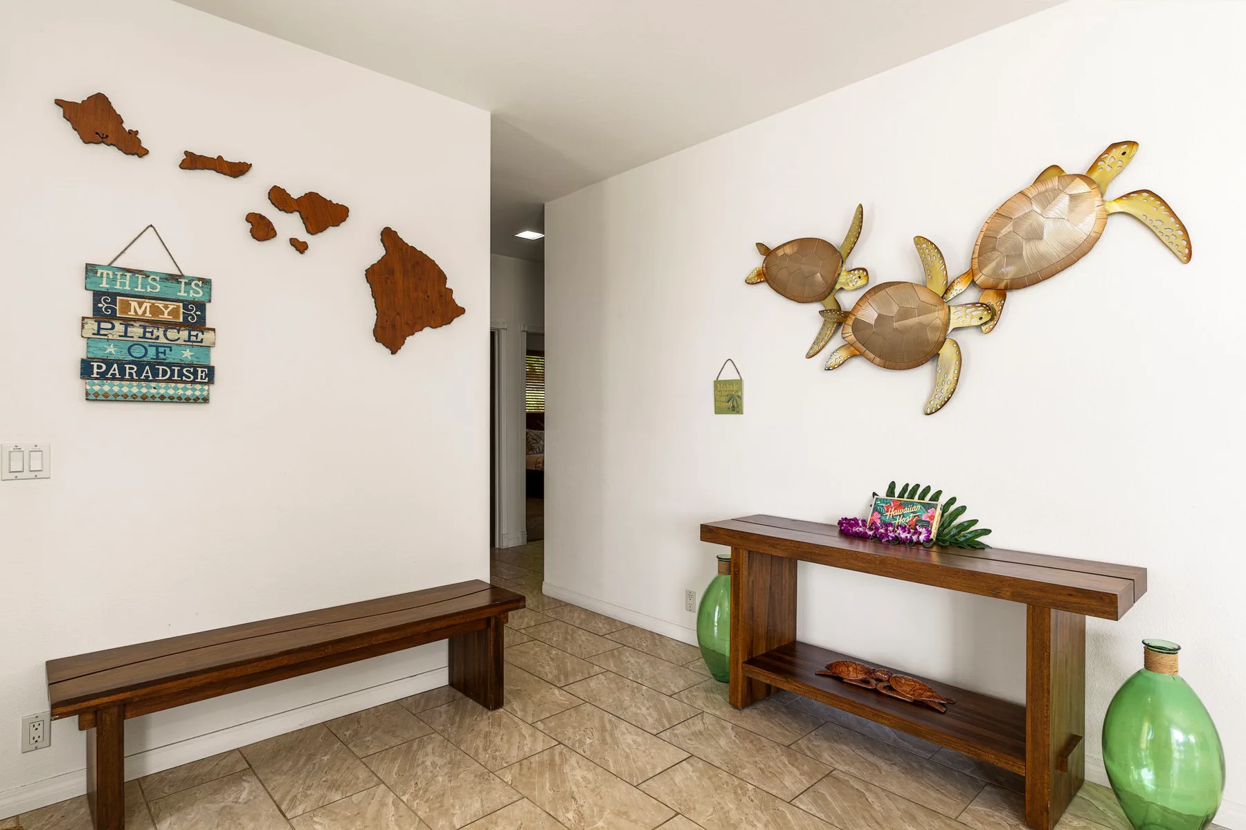 A bright entryway features a wooden bench and a console table beneath turtle wall decorations.