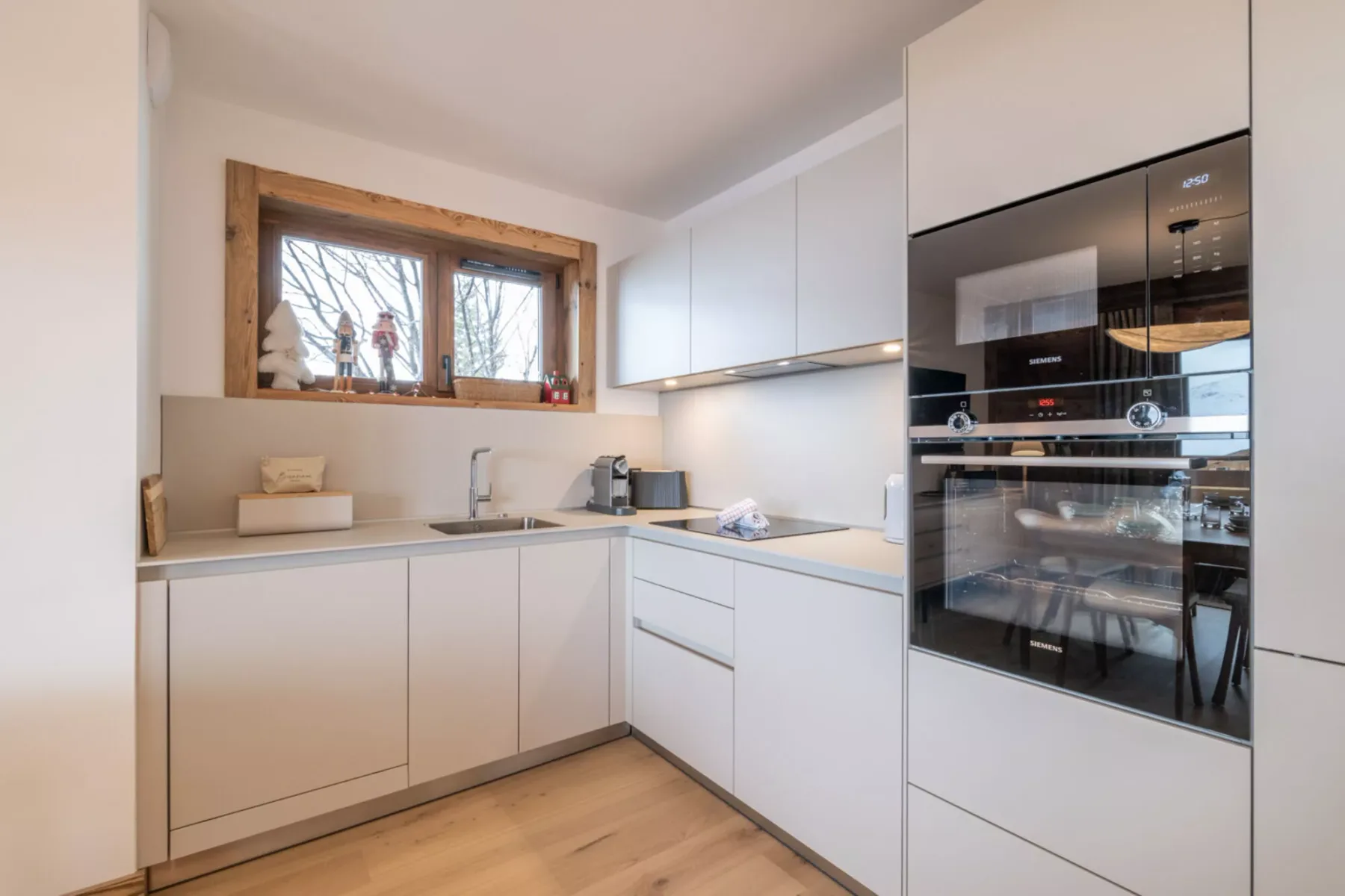 A modern kitchen with pale cabinets, a countertop, and a built-in oven.