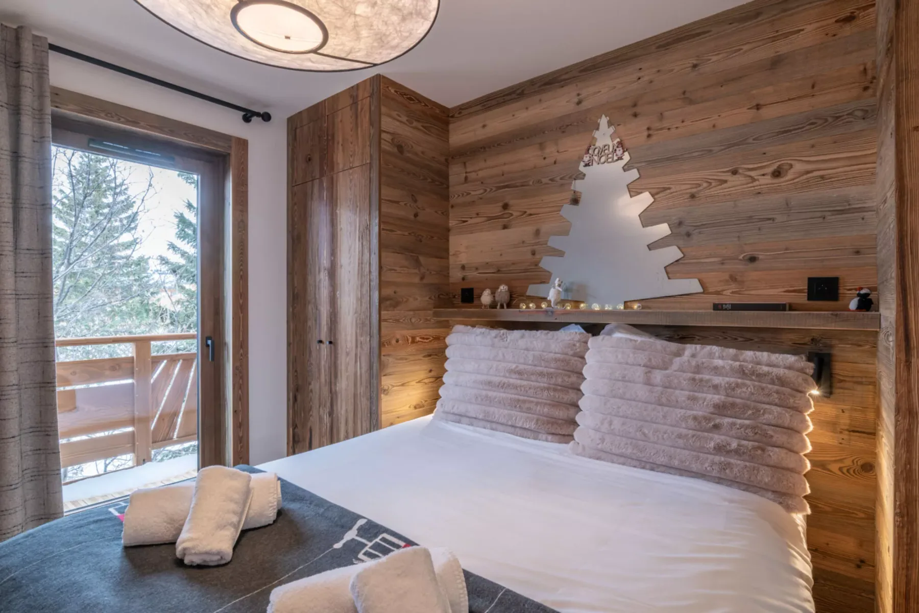 A bedroom with a bed against a wood-paneled wall and a glass door to a balcony.