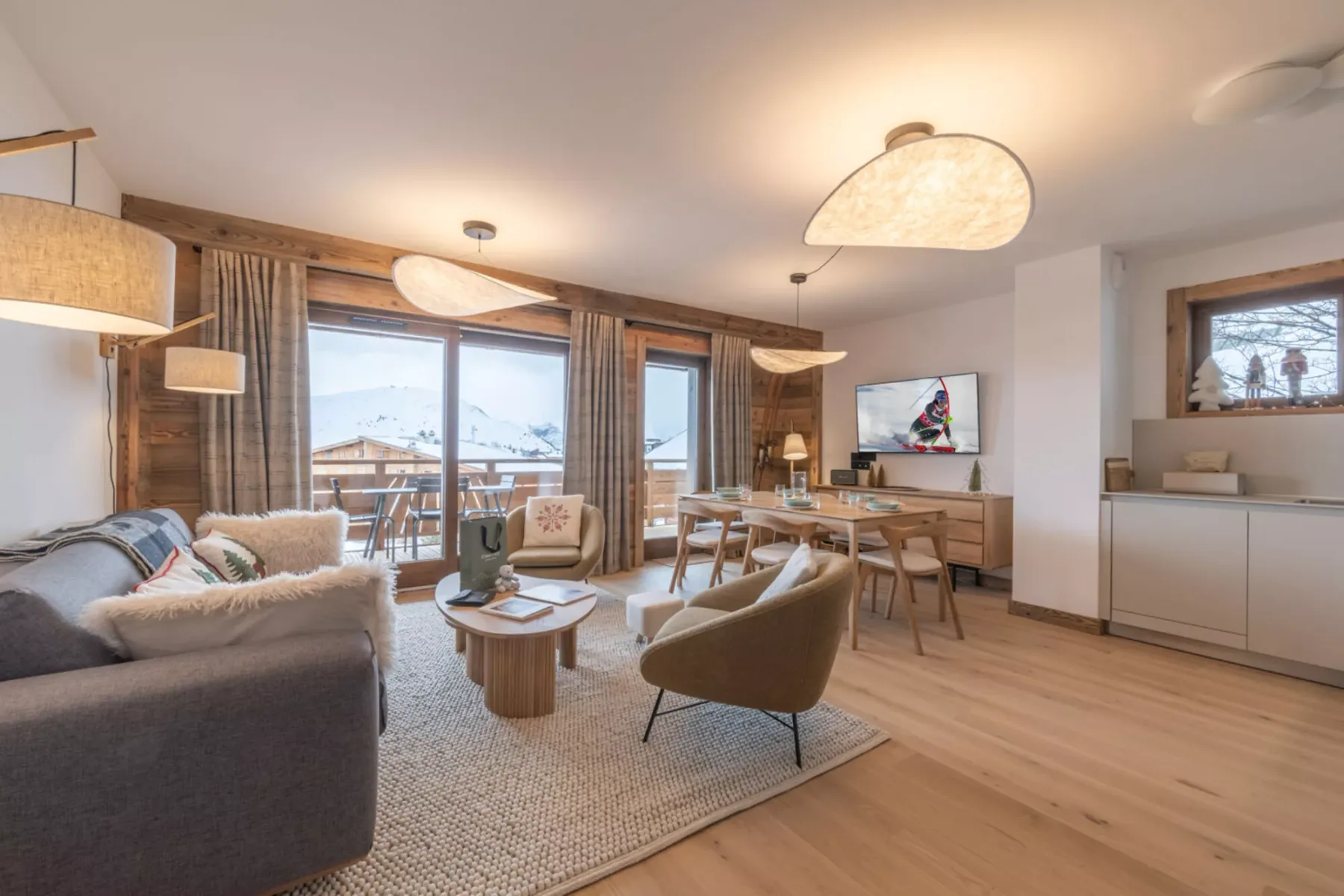 A living room with seating around a coffee table beside large windows.