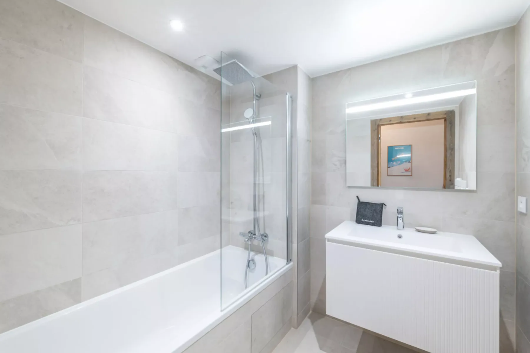 A bright bathroom with a bathtub, glass shower screen, and vanity.