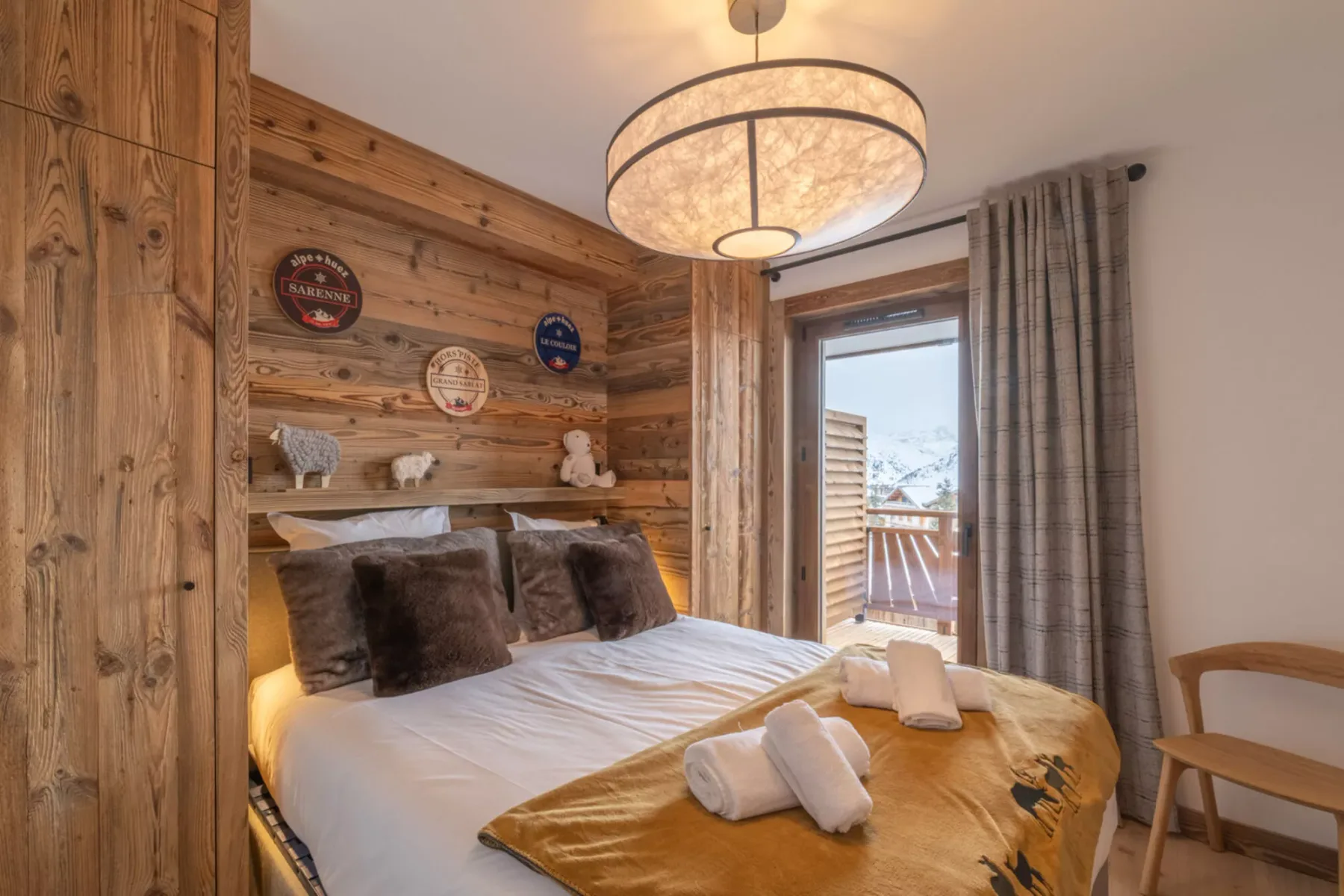 A bedroom with a bed dressed in white linens and a mustard-colored cover.