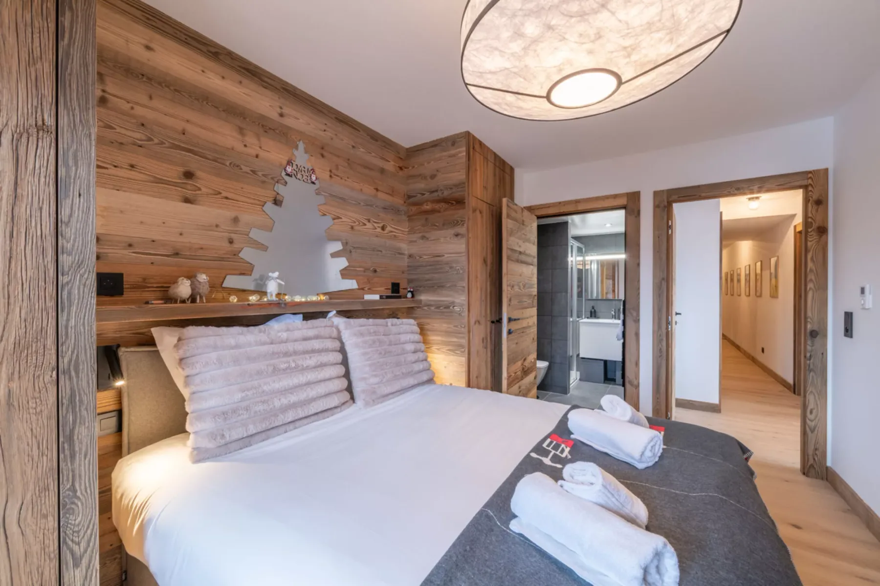 A bedroom with a neatly made bed and wood-paneled walls.