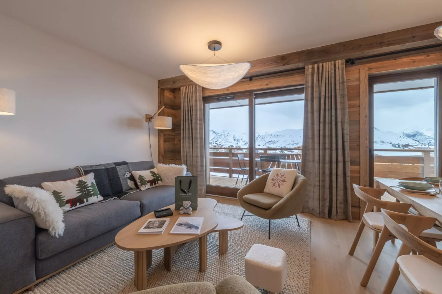 A living room with seating, a coffee table, and large windows overlooking a snowy landscape.