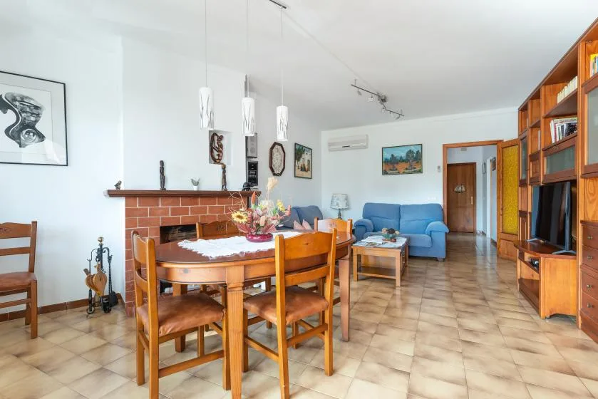 Una sala de estar y comedor con una mesa de madera, asientos azules y una chimenea.