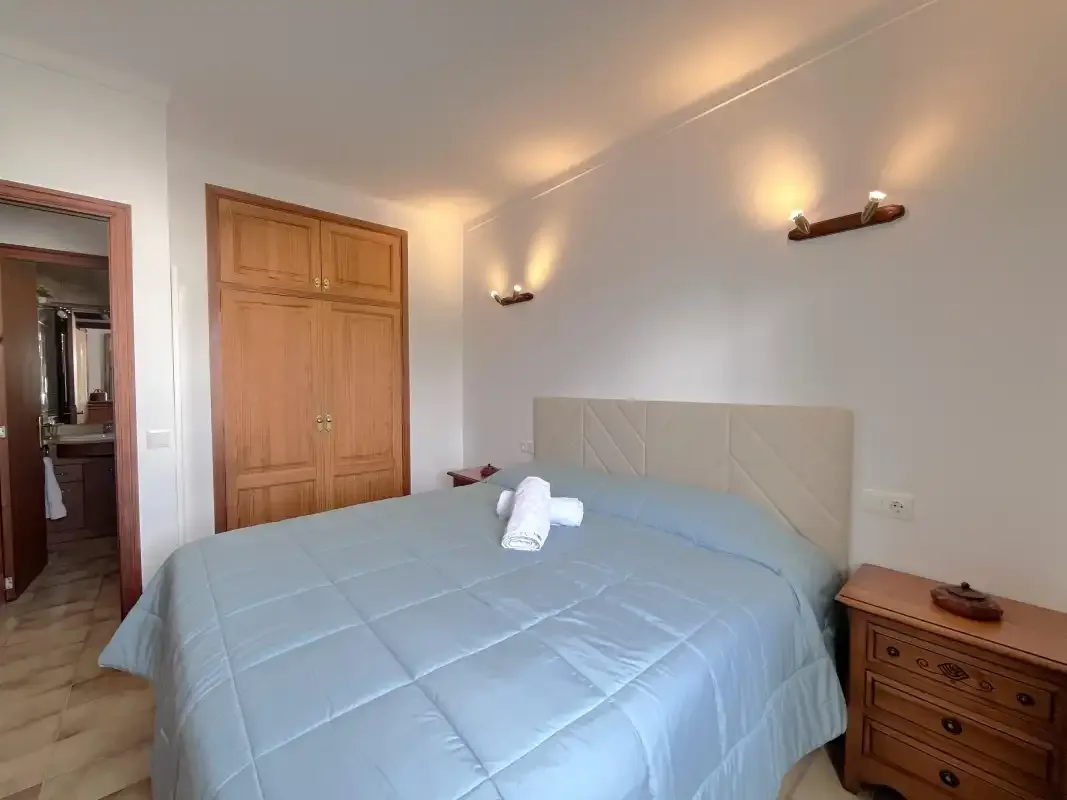 Un dormitorio con una cama, mesillas de noche y luces de pared.