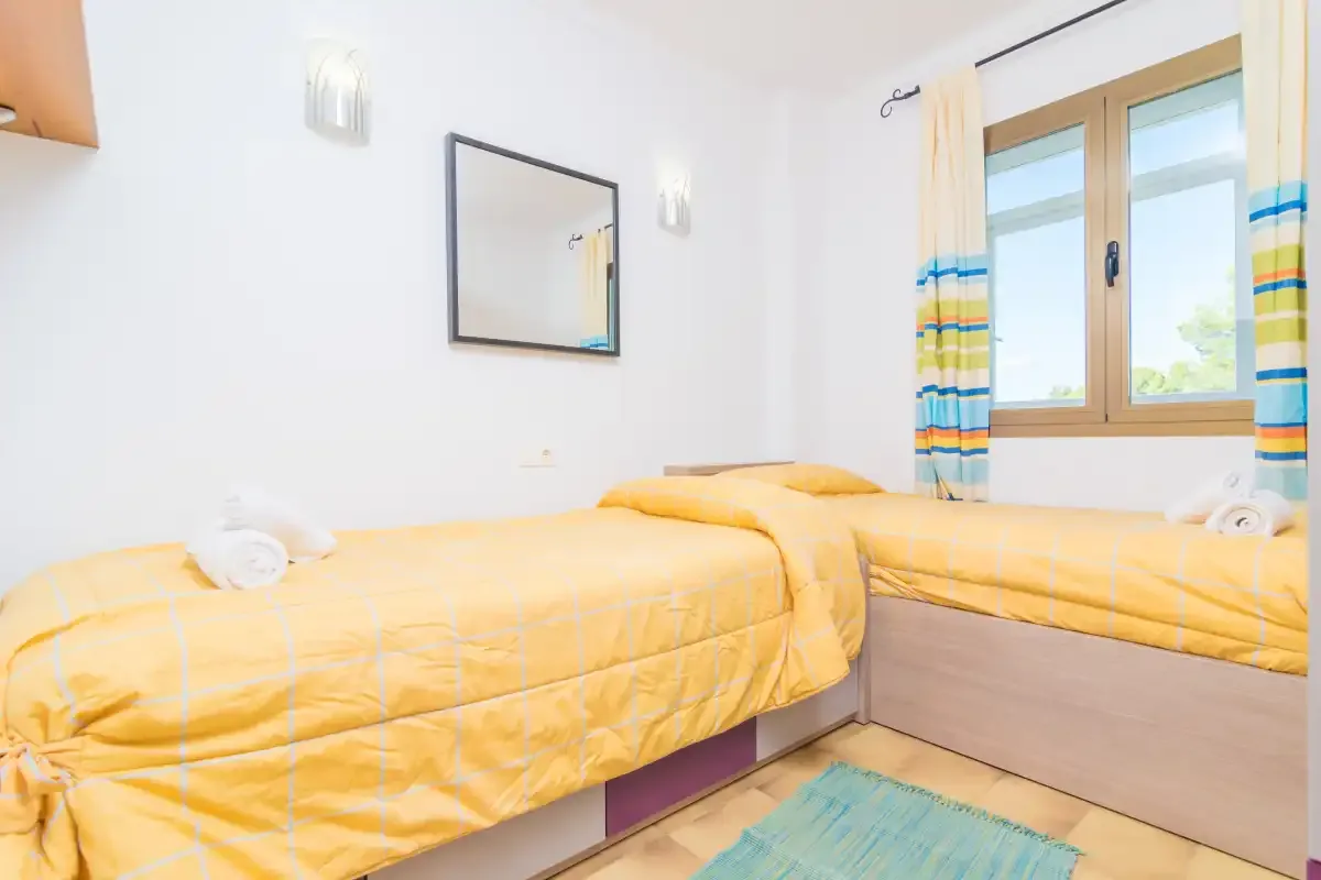 Un dormitorio con ropa de cama amarilla y una ventana.