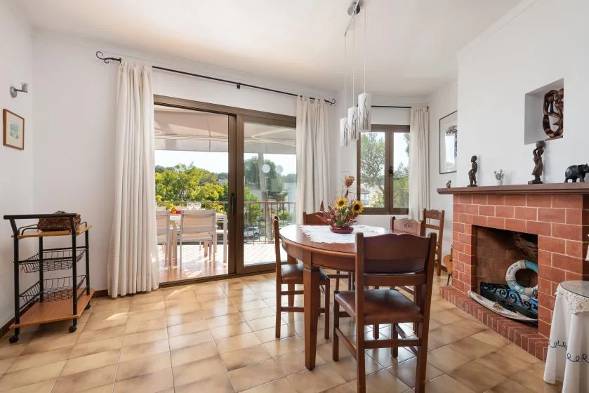 Un comedor con una mesa de madera junto a puertas de vidrio que dan a un patio.