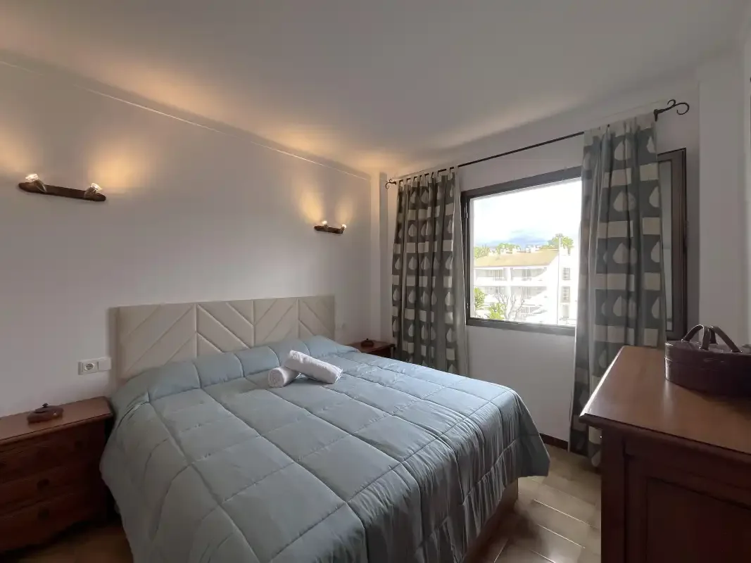 Un dormitorio con una cama doble y una ventana con cortinas.