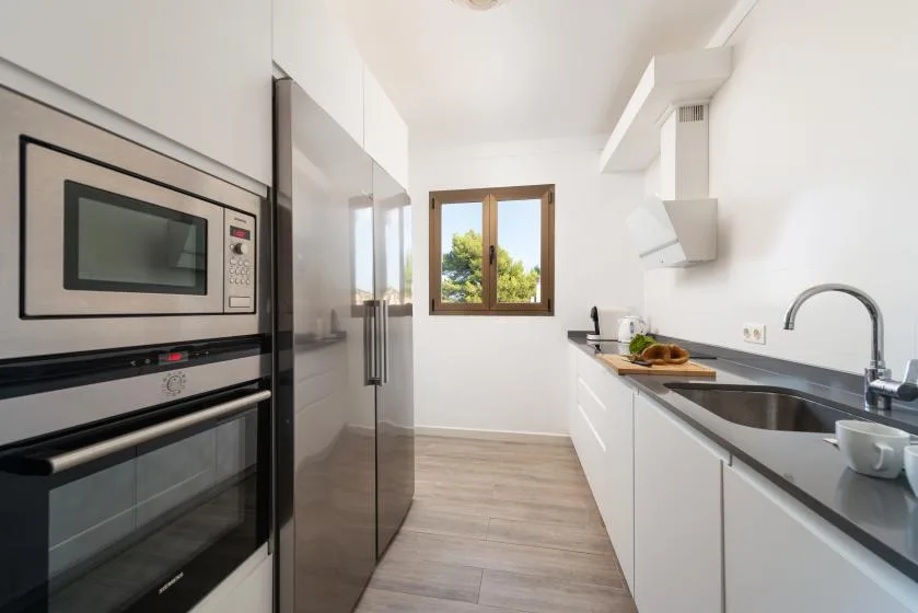 Una cocina moderna y luminosa con electrodomésticos integrados y una encimera larga.