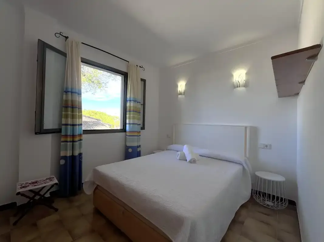 Un dormitorio con una cama junto a una ventana con cortinas a rayas.