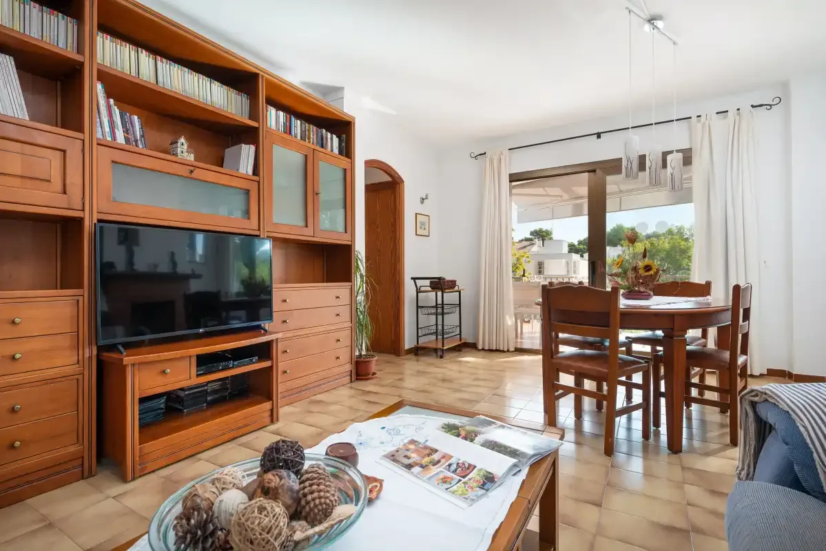 Una sala de estar y comedor con asientos de madera y un televisor.